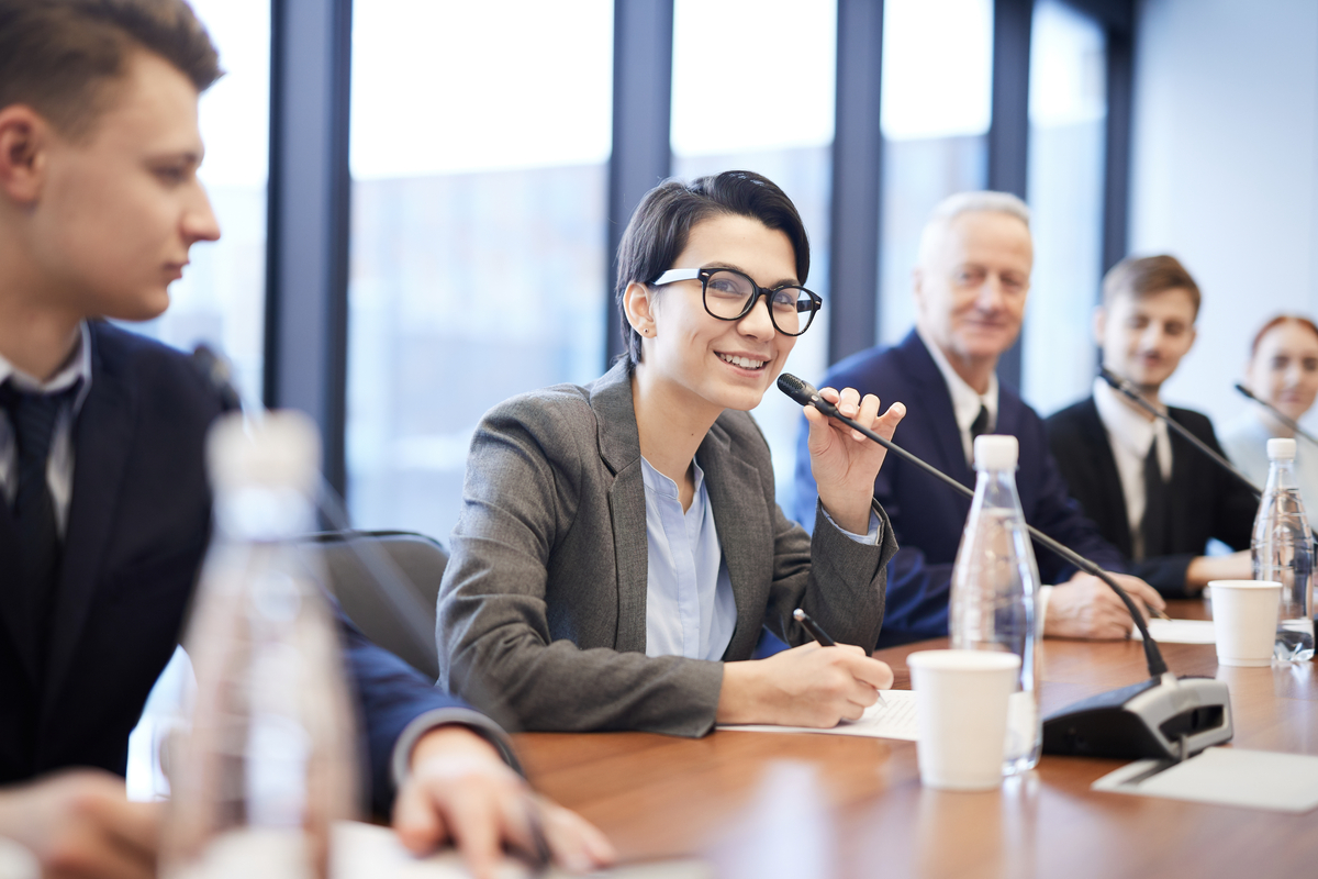 smiling young businesswoman speaking at conference